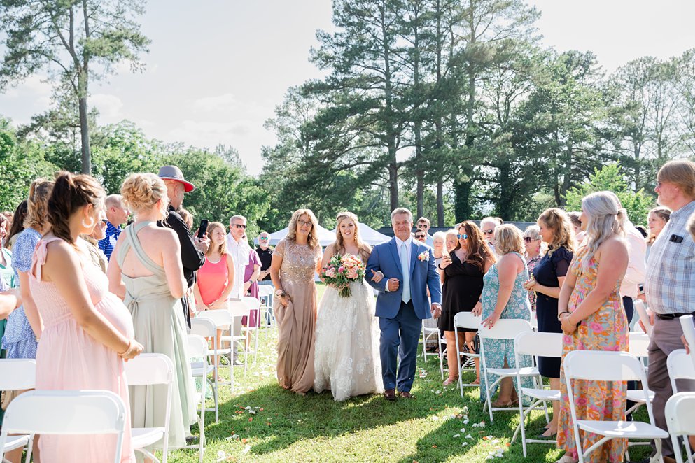 summer wedding bouquet with coral and pink flowers and a lace gown