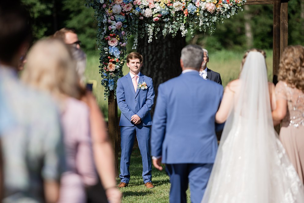 summer wedding bouquet with coral and pink flowers and a lace gown