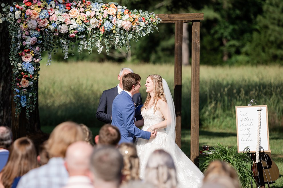 summer wedding bouquet with coral and pink flowers and a lace gown