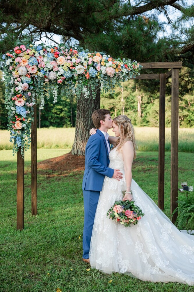 summer wedding bouquet with coral and pink flowers and a lace gown