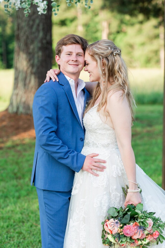 summer wedding bouquet with coral and pink flowers and a lace gown